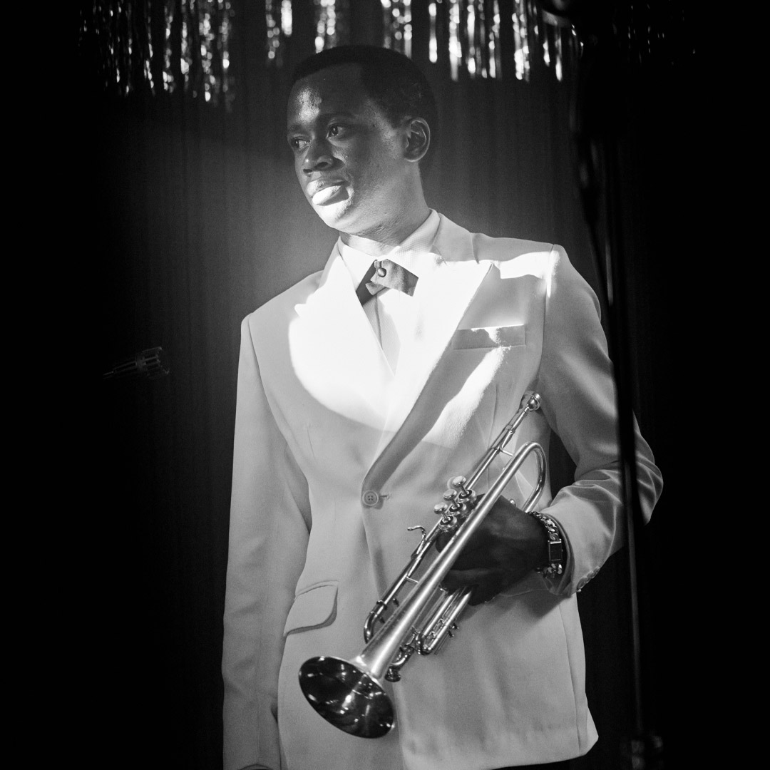 Grayscale photo of same musician holding trumpet