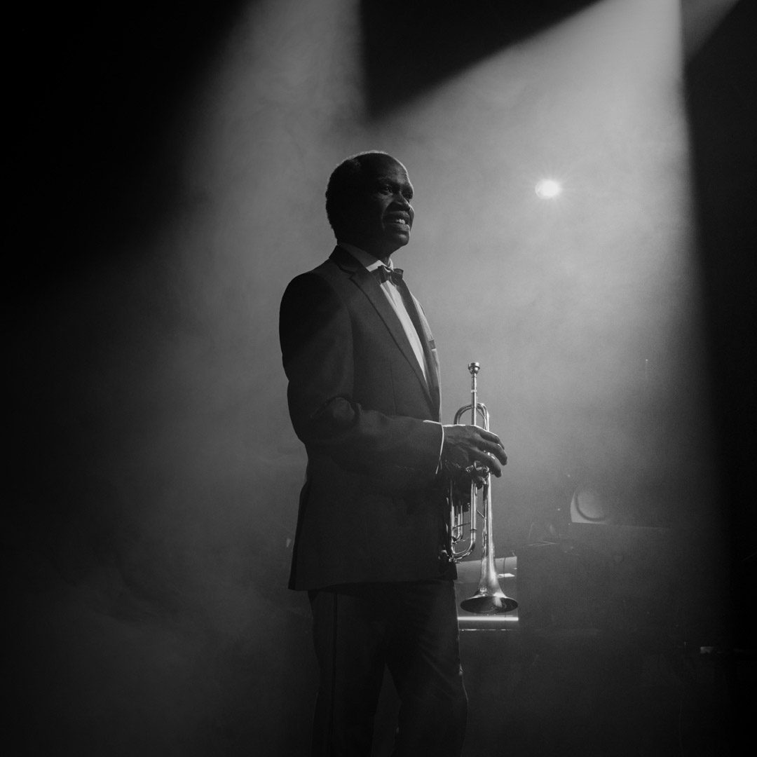 Grayscale photo of same older musician performing on stage