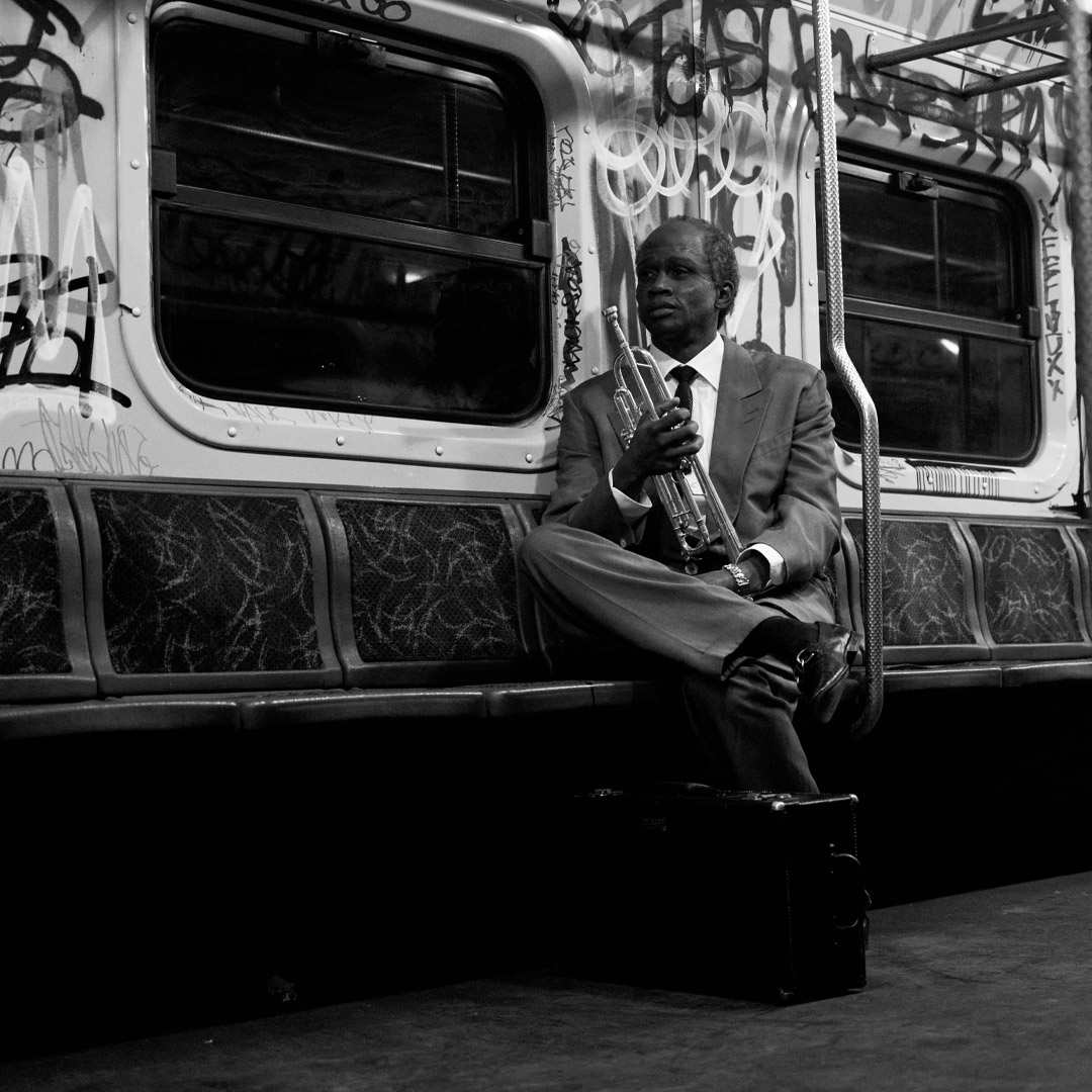 Grayscale photo of same older musician holding trumpet